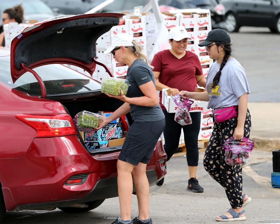 Volunteers, from left, Kelly Davis, Sandra Hernandez and Anna Dang load fresh fruit at the distribution line for the Antioch for Youth & Family Child Summer Feeding Program in Fort Smith, Ark.