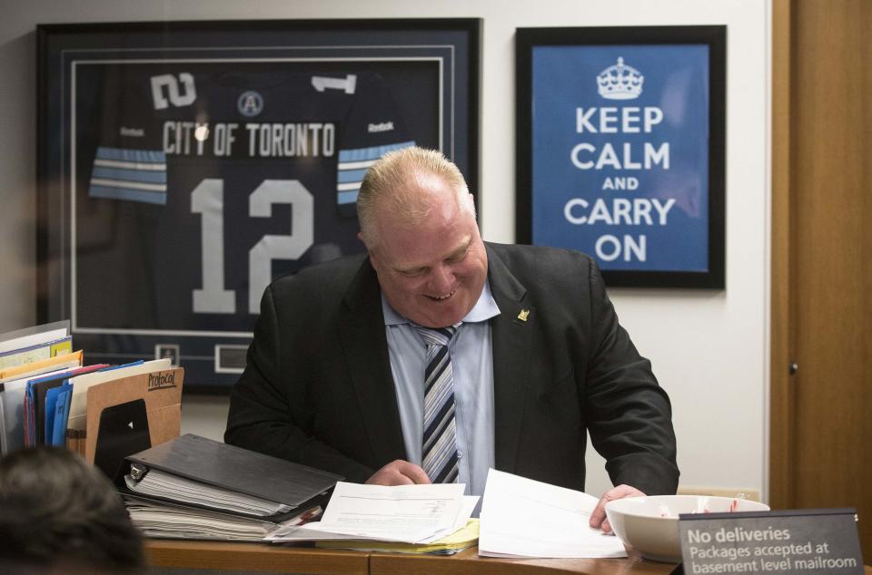 Toronto Mayor Ford laughs in front of a sign that says "Keep Calm and Carry On" at City Hall in Toronto