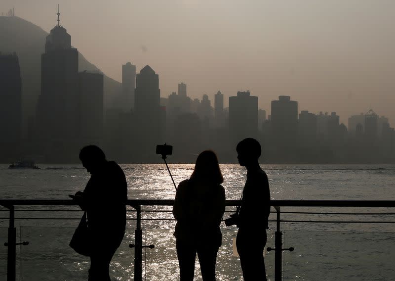 FILE PHOTO: A couple takes a selfie during sunset on a waterfront facing the financial Central district in Hong Kong