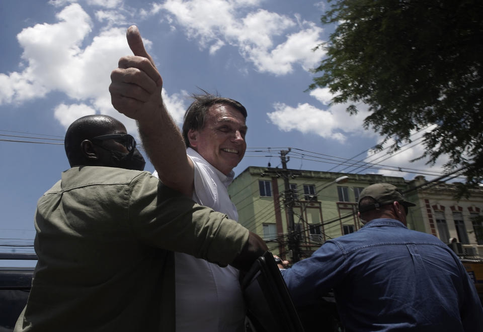 Brazil's President Jair Bolsonaro greets supporters after voting during the run-off municipal elections in Rio de Janeiro, Brazil, Sunday, Nov. 29, 2020. Bolsonaro, who sometimes has embraced the label "Trump of the Tropics," said Sunday he'll wait a little longer before recognizing the U.S. election victory of Joe Biden, while also echoing President Donald Trump's allegations of irregularities in the U.S. vote. (AP Photo/Silvia Izquierdo)