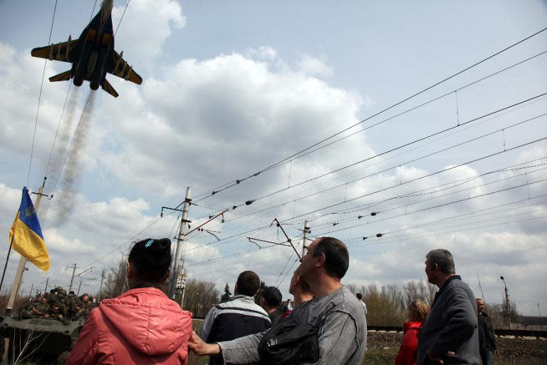 Ukrainian MIG 295 fighter plane flies above pro-Russian activists blocking a column of Ukrainian armoured personnel carriers in the eastern Ukrainian city of Kramatorsk on April 16, 2014