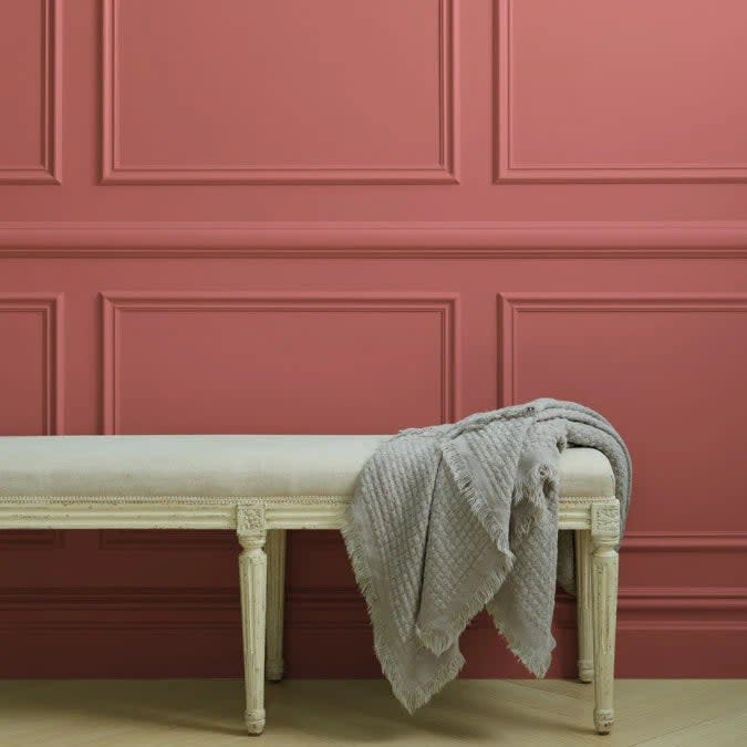 Long upholstered bench with taupe throw blanket, against a wainscoted wall painted in Pink Sky by Clare.