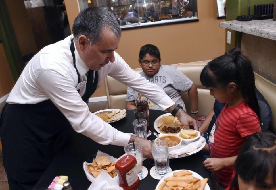 Gerardo Amezola, a la izquierda, sirve comida a los hijos de Jesse Toledo, en esta foto de archivo de 2017.