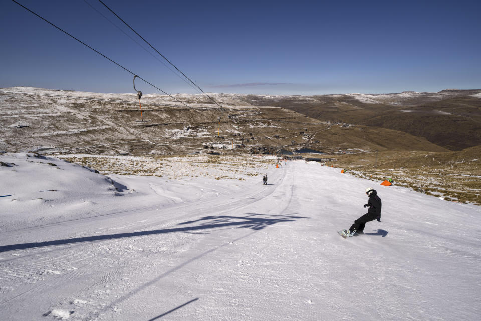 A snowboarder slides down the slope of the Afriski ski resort near Butha-Buthe, Lesotho, Saturday July 30, 2022. While millions across Europe sweat through a summer of record-breaking heat, Afriski in the Maluti Mountains is Africa's only operating ski resort south of the equator. It draws people from neighboring South Africa and further afield by offering a unique experience to go skiing in southern Africa. (AP Photo/Jerome Delay)