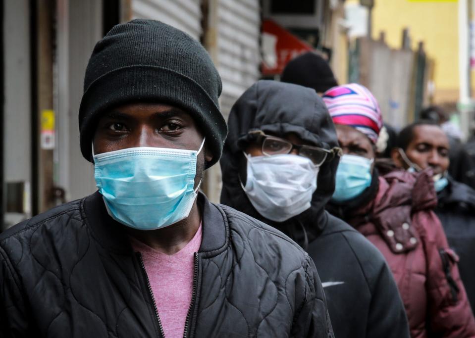 People wait for the distribution of masks and food from the Rev. Al Sharpton in the Harlem neighborhood of New York on April 18, 2020, after a state mandate was issued requiring residents to wear face coverings in public due to COVID-19.