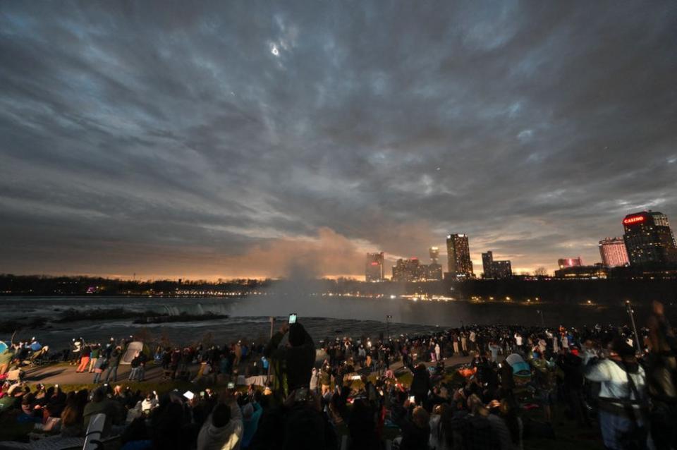 The sky darkens as people watch during totality of the total solar eclipse across North America, at Niagara Falls State Park in Niagara Falls, New York, on April 8, 2024.