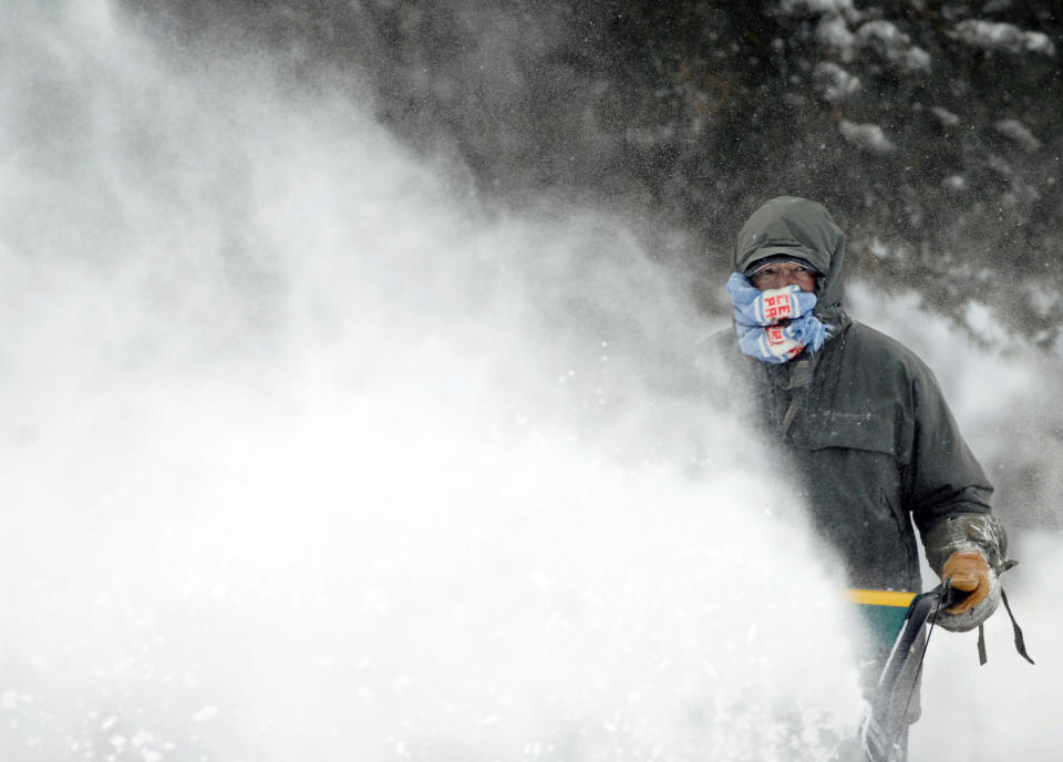 Errol Behm uses a scarf to shield his face from the blow-back of snow caused by the gusty winds as he clears a sidewalk with a snow blower near Fourth Street Thursday, Dec. 27, 2018, in Bismarck, N.D. Forecasters posted a blizzard warning for parts of the Dakotas and Minnesota as a major winter storm delivered heavy snow and gusty winds to the region. (Mike McCleary/The Bismarck Tribune via AP)