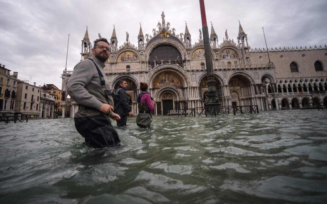 Tourists walking through the flooded St Mark's Square in Venice - Filippo Monteforte/AFP