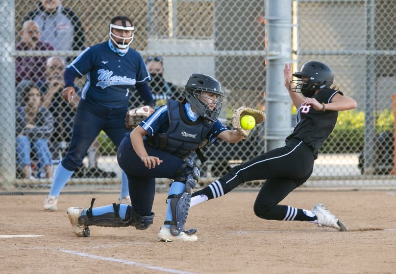 Huntington Beach's Emma Francisco beats the tag from Marina's Zoe King to score in the first inning during a Surf League softball game at Huntington Beach High School on Wednesday, April 28.