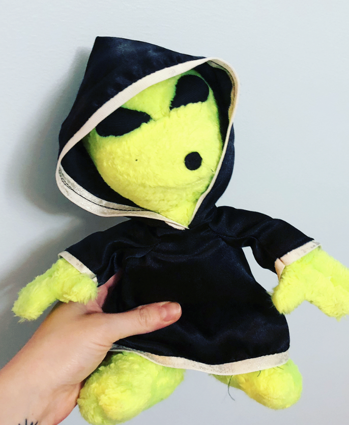 an alien plushie in a hooded robe
