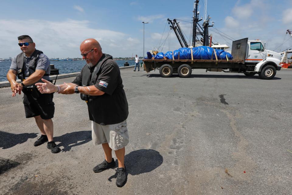 Fairhaven harbormaster Timothy Cox washes his hands after loading the small whale, which was found dead in New Bedford harbor onto the truck seen in the background, at Union Wharf in Fairhaven.