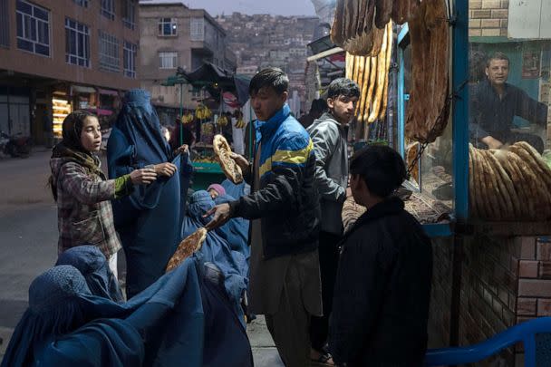 PHOTO: A man distributes bread to Afghan women outside a bakery in Kabul, Afghanistan, Dec, 2, 2021.  (Petros Giannakouris/AP, FILE)