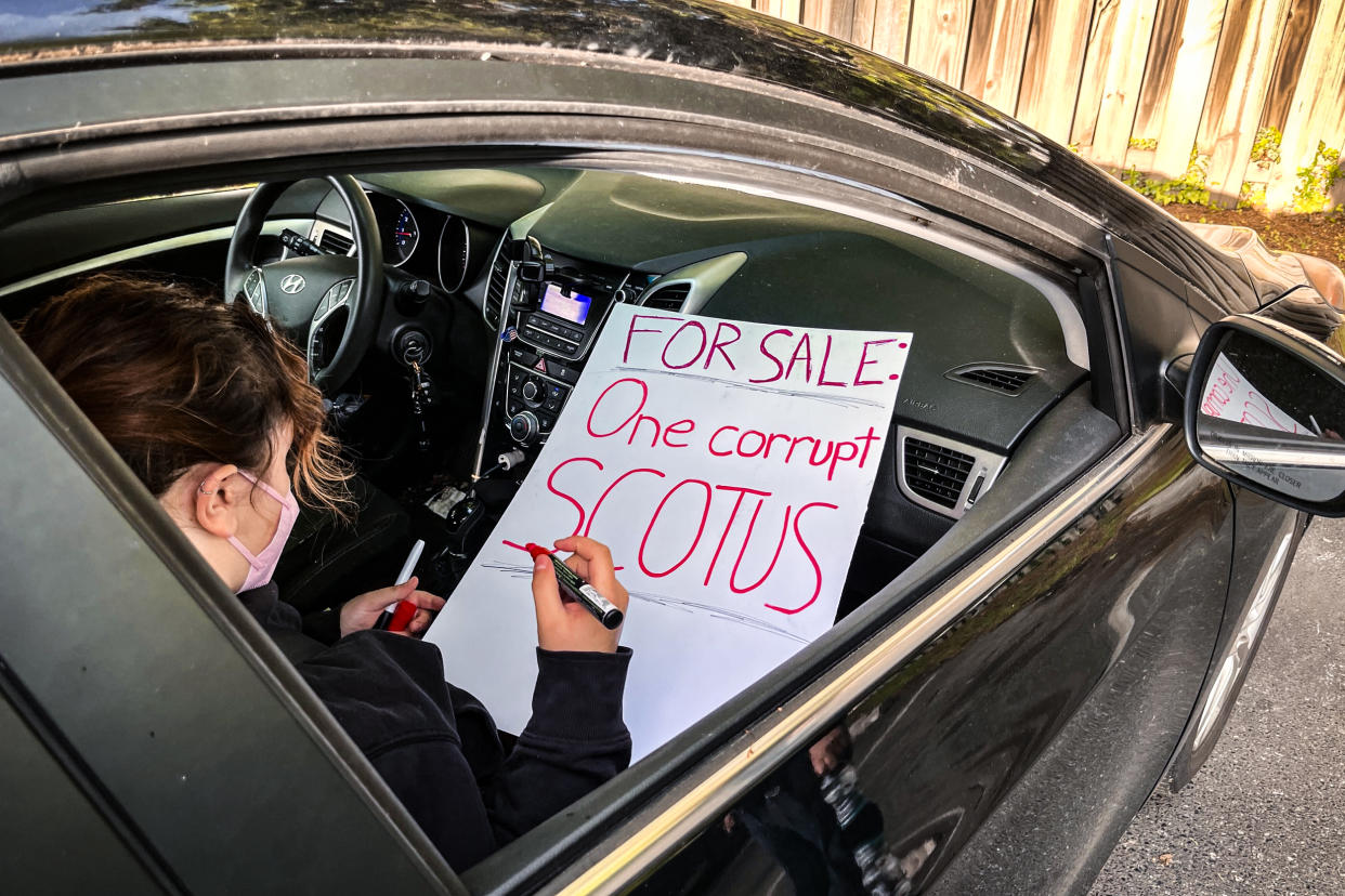 A woman prepares a sign critical of the Supreme Court before joining a protest outside the homes of Justice Brett Kavanaugh and Chief Justice John Roberts on May 4, 2023. (Lawrence Hurley / NBC News)