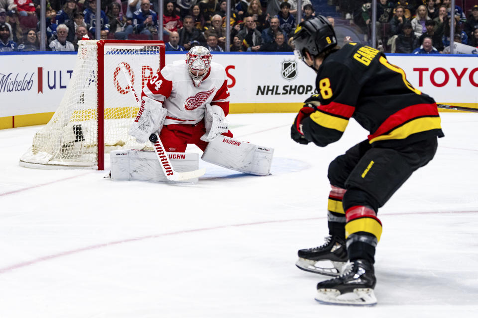 Detroit Red Wings goaltender Alex Lyon (34) stops a shot by Vancouver Canucks' Conor Garland (8) during the first period of an NHL hockey game Thursday, Feb. 15, 2024, in Vancouver, British Columbia. (Ethan Cairns/The Canadian Press via AP)