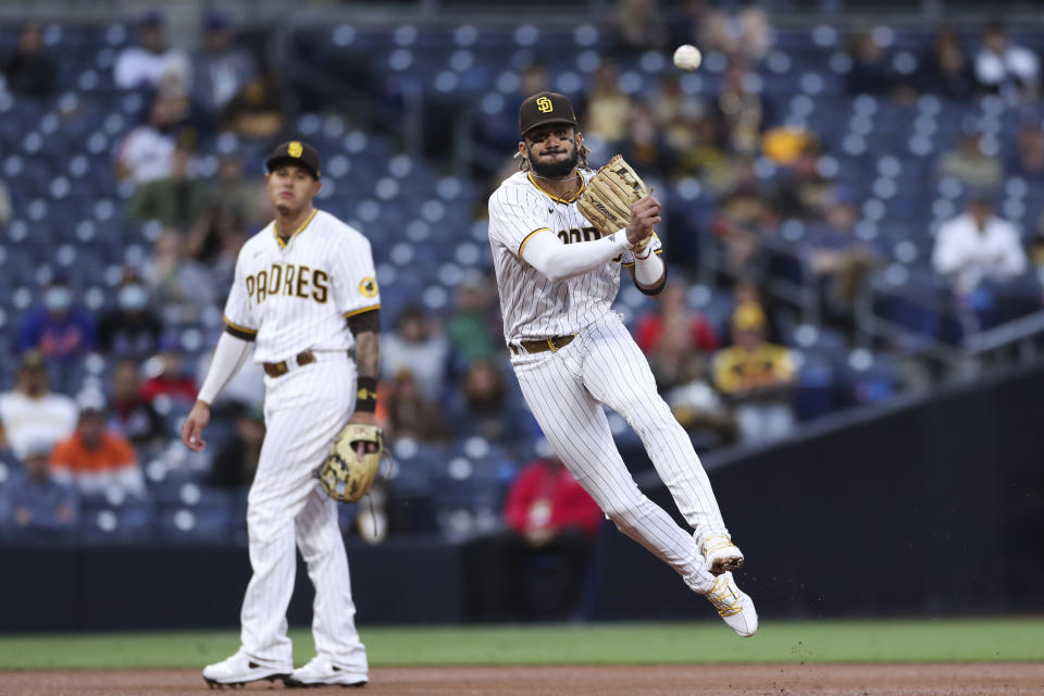 San Diego Padres shortstop Fernando Tatis Jr. throws to first base after fielding a grounder by New York Mets' Kevin Pillar as Manny Machado, left, looks on in the second inning of a baseball game Saturday, June 5, 2021, in San Diego. Pillar was out at first. (AP Photo/Derrick Tuskan)