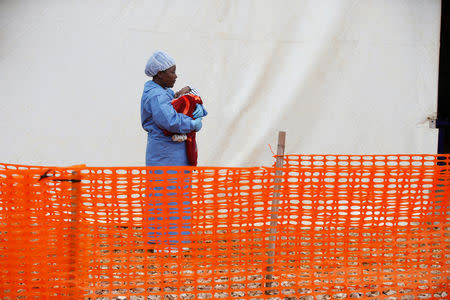 Rachel Kahindo, Ebola survivor working as a caregiver to babies who are confirmed Ebola cases, holds an infant outside the red zone at the Ebola treatment centre in Butembo, Democratic Republic of Congo, March 25, 2019. Picture taken March 25, 2019.REUTERS/Baz Ratner