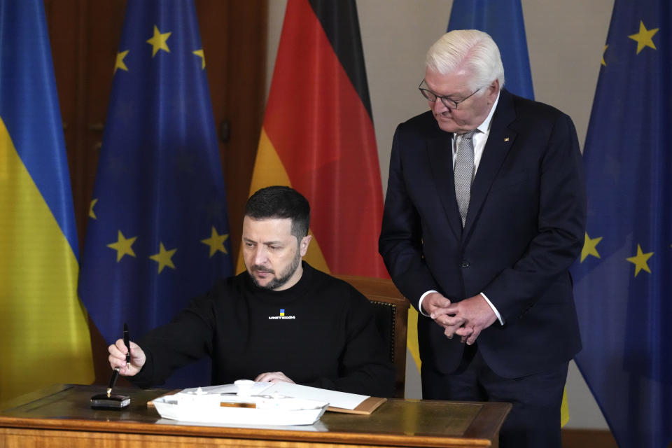 Germany's President Frank-Walter Steinmeier, right, looks on as Ukraine's President Volodymyr Zelenskyy prepares to sign the Golden Book at the Bellevue Palace in Berlin, Germany, Sunday, May 14, 2023. Ukrainian President Volodymyr Zelenskyy arrived in Berlin early Sunday for talks with German leaders about further arms deliveries to help his country fend off the Russian invasion and rebuild what's been destroyed by more than a year of devastating conflict. (AP Photo/Matthias Schrader)