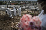 Trabajadores de un cementerio, vestidos con trajes de protección, cierran la tumba de Ana María, una ayudante de enfermería de 56 años que falleció a causa del coronavirus, en Río de Janeiro, Brasil, el 28 de abril de 2020. (AP Foto/Leo Correa)