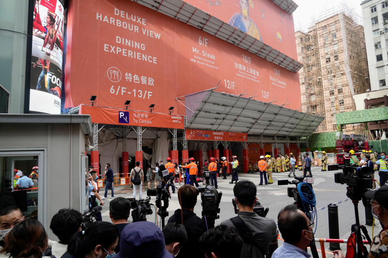 People walk out from the World Trade Centre where is located in the city's popular Causeway Bay shopping district of Hong Kong, Wednesday, Dec. 15, 2021. Dozens of people are trapped on the rooftop of the Hong Kong skyscraper after a major fire broke out Wednesday, as firefighters rushed to rescue them and put out the blaze. (AP Photo/Kin Cheung)