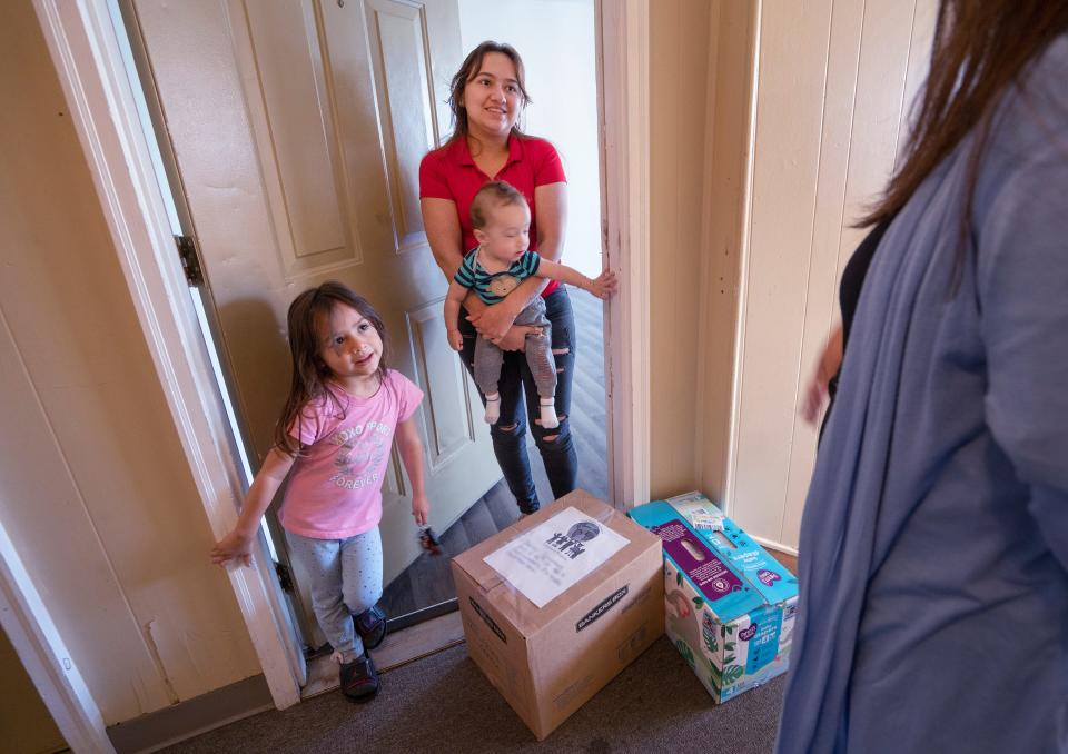 Deisy Sanchez, left, standing with her children, Megan and Dennis, is happy with the care package delivered by Grassroot Projects Program Coordinator Rosana Marin, Monday, Nov. 7, 2022. The small nonprofit organization helps children of immigrant and refugee families.