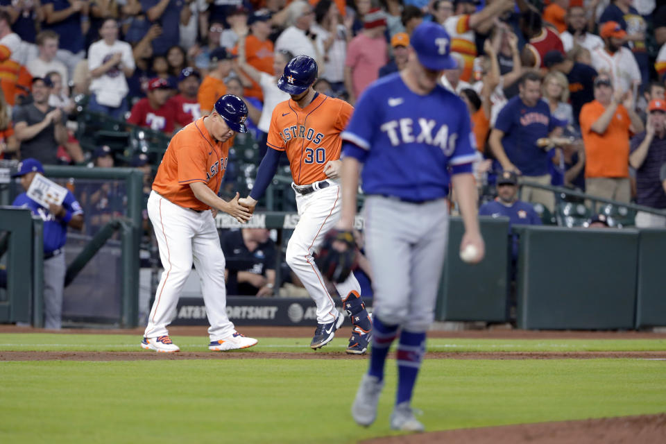 Houston Astros third base coach Omar Lopez, left, and Kyle Tucker, center, celebrate as Tucker rounds the bases on his three-un home run as Texas Rangers starting pitcher Kolby Allard, right, heads back to the mound during the third inning of a baseball game Friday, July 23, 2021, in Houston. (AP Photo/Michael Wyke)