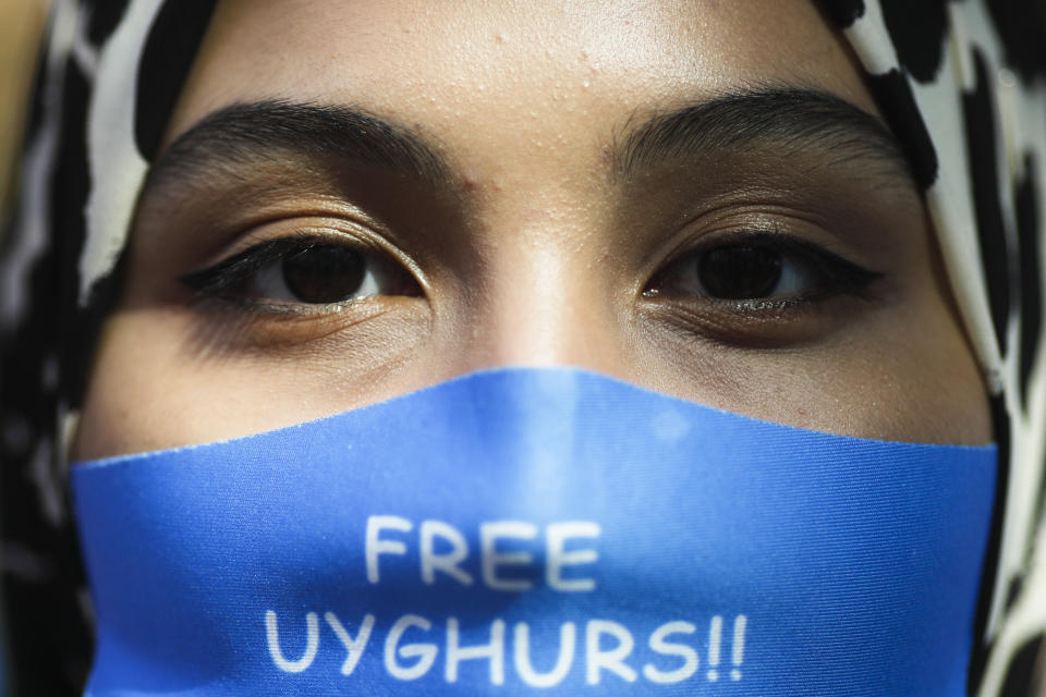 A woman wears a face mask reading 'Free Uyghurs' as she attends a protest during the visit of Chinese Foreign Minister Wang Yi in Berlin, Germany, Tuesday, Sept. 1, 2020. German Foreign Minister Heiko Maas meets his Chinese counterpart at the foreign ministry guest house Villa Borsig for bilateral talks. (AP Photo/Markus Schreiber)