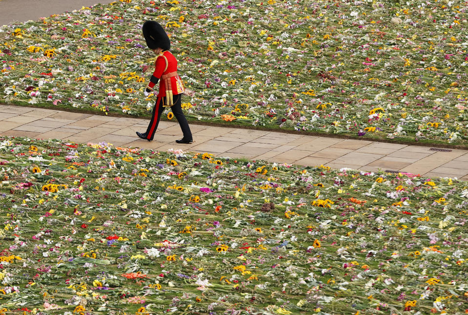 <p>A member of the Coldstream Guards is seen walking past a bed of flowers during the state funeral. (Getty Images)</p> 