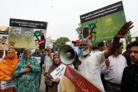 FILE PHOTO: People hold signs as they chant slogans against the participation of banned outfits to take part in general elections, during a protest outside election commission office in Karachi, Pakistan July 16, 2018. REUTERS/Akhtar Soomro/File Photo