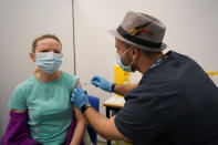 A woman receives a dose of the Pfizer COVID-19 vaccine at Swaminarayan School vaccination centre, in London, Saturday, Dec. 4, 2021. Britain says it will offer all adults a booster dose of vaccine within two months to bolster the nation's immunity as the new omicron variant of the coronavirus spreads. New measures to combat variant came into force in England on Tuesday, with face coverings again compulsory in shops and on public transport. (AP Photo/Alberto Pezzali)