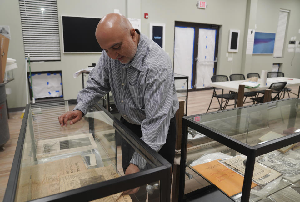 Tahir Ahmed Soofi, president of the Zion Ahmadiyya Muslim Community's Zion Chapter, looks through articles and artifacts in an unfinished display case in the newly constructed Fath-e-Azeem mosque on Thursday, Sept. 15, 2022. The mosque will display newspapers, books and photographs about a prayer duel that took place between the Ahmadi Muslim founder, Mirza Ghulam Ahmad, and Christian faith healer and Zion founder, John Alexander Dowie. The small-sized city, 40 miles north of Chicago, is a place of special religious significance for their global messianic faith because they feel their prophet won this century-old duel. (AP Photo/Jessie Wardarski)