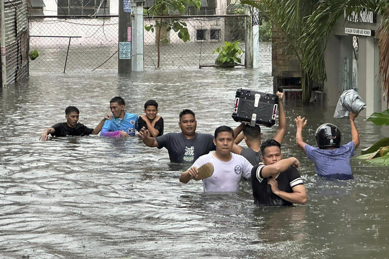 People walk through a street in Manila flooded from monsoon rains worsened by offshore Typhoon Gaemi on Wednesday.