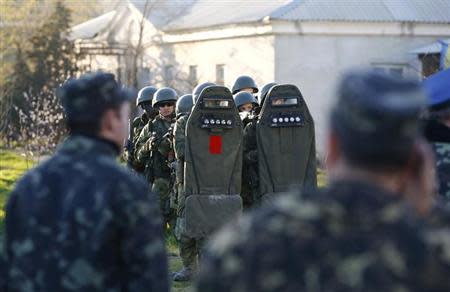 Armed men, believed to be Russian servicemen, stand guard, with Ukrainian servicemen seen in the foreground, at a military airbase, in the Crimean town of Belbek near Sevastopol March 22, 2014. REUTERS/Shamil Zhumatov