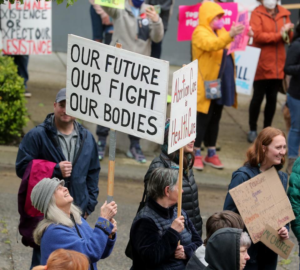 Carollynn Zimmers, of Poulsbo, looks up as she spins her sign around during a rally for reproductive rights at the Norm Dicks Government Center in Bremerton on Friday.