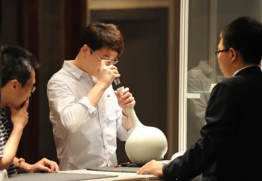 A visitor is seen inspecting a Chinese ancient art work at a preview show of an auction house in Beijing, in May. Until recently, few in the art world had even heard of China's auction houses. Today, they are among the world's biggest by revenue, posing a serious challenge to the likes of Sotheby's and Christie's