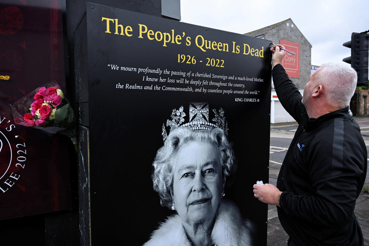 A man installs a plaque depicting Britain's Queen Elizabeth II.