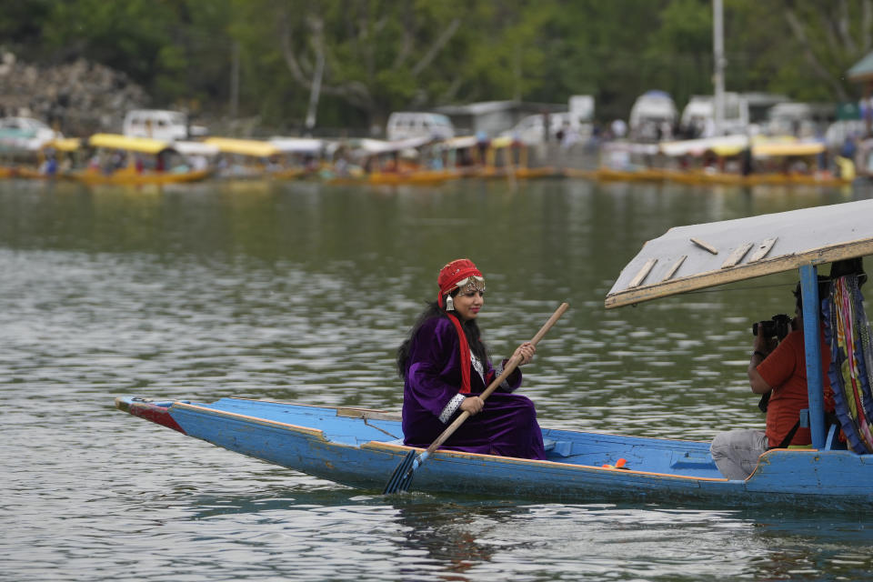 An Indian tourist in a Kashmiri attire poses for photographs in a boat at the Dal Lake in Srinagar, Indian controlled Kashmir, Wednesday, May 17, 2023. Indian authorities have stepped up security and deployed elite commandos to prevent rebel attacks during the meeting of officials from the Group of 20 industrialized and developing nations in the disputed region next week. (AP Photo/Mukhtar Khan)