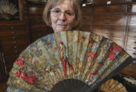 Anne Hoguet, 74, fan maker and director of the hand fan-making museum poses with a wood roasted hand fan representing a falcon hunt, gouache painting g on paper from 1880 at the museum in Paris, Wednesday, Jan. 20, 2021. Just like the leaves of its gilded fans, France's storied hand fan-making museum could fold up and vanish. The splendid Musee de l'Eventail in Paris, a classed historical monument, is the culture world's latest coronavirus victim. (AP Photo/Michel Euler)