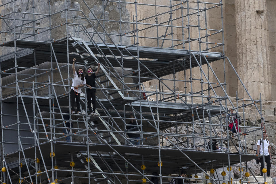 Protesters shout slogans from scaffolding at the Acropolis hill, in Athens, Greece, Sunday, Oct. 17, 2021. Three people attempted to hang a banner from the Acropolis in Athens Sunday morning in protest at the upcoming Beijing Winter Olympics but were arrested before completing their mission. (AP Photo/Yorgos Karahalis)