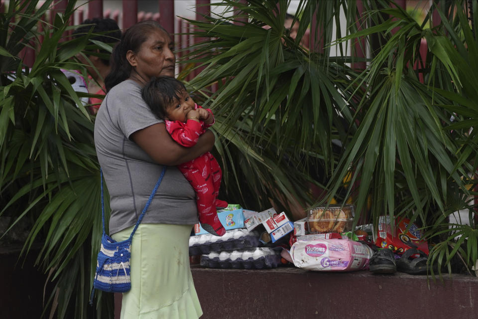 A woman holds a baby next to some goods taken from stores after Hurricane Otis ripped through Acapulco, Mexico, Wednesday, Oct. 25, 2023. Hurricane Otis ripped through Mexico's southern Pacific coast as a powerful Category 5 storm, unleashing massive flooding, ravaging roads and leaving large swaths of the southwestern state of Guerrero without power or cellphone service. (AP Photo/Marco Ugarte)