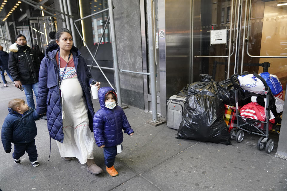 A pregnant woman and children who left the Row Hotel walk past the belongings of other immigrants, Tuesday, Jan. 9, 2024, in New York. (AP Photo/Mary Altaffer)