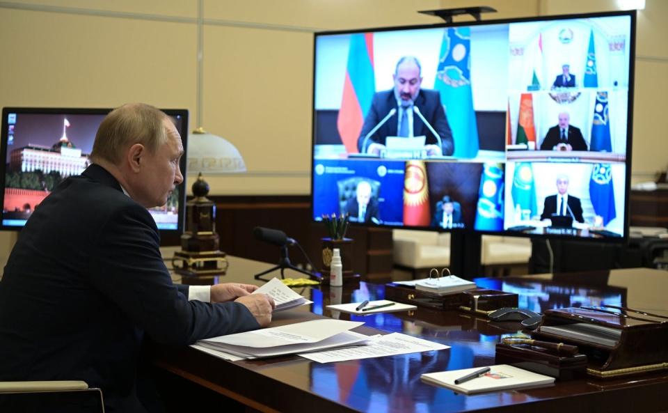 Vladimir Putin sits in front a screen on which other regional leaders are seen.