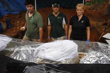 Volunteer Brett Harding (L), University of South Florida associate professor Chistian Wells, and assistant professor Erin Kimmerle (R) look at a body bag containing remains removed from an unmarked grave at the now closed Arthur G. Dozier School for Boys in Marianna, Florida, September 2, 2013. REUTERS/Edmund D. Fountain/Pool