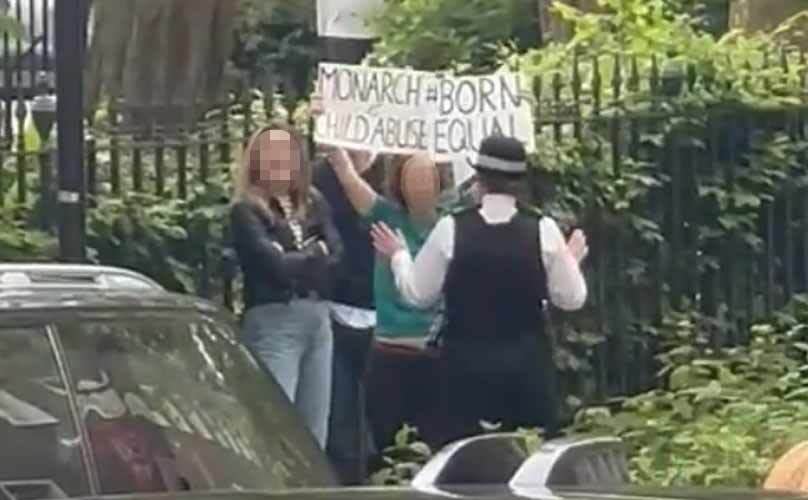 The protester holding placards as the Princess of Wales arrived on Thursday. (@RoyalReporter/Twitter)