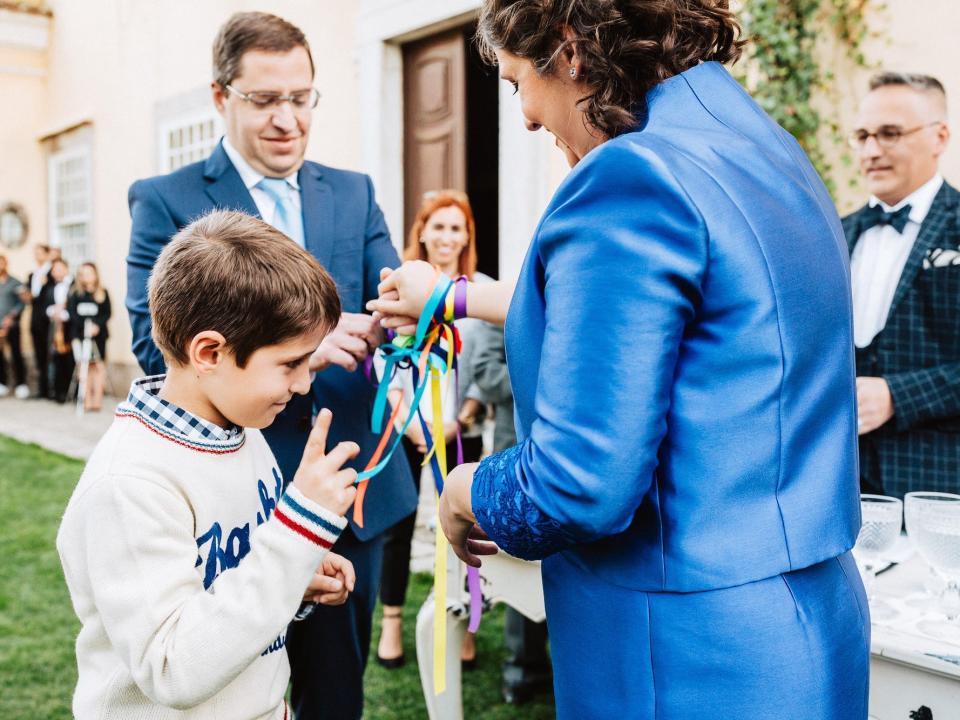 A boy stands between his parents as they tie ribbons around their wrists for their vow renewal.