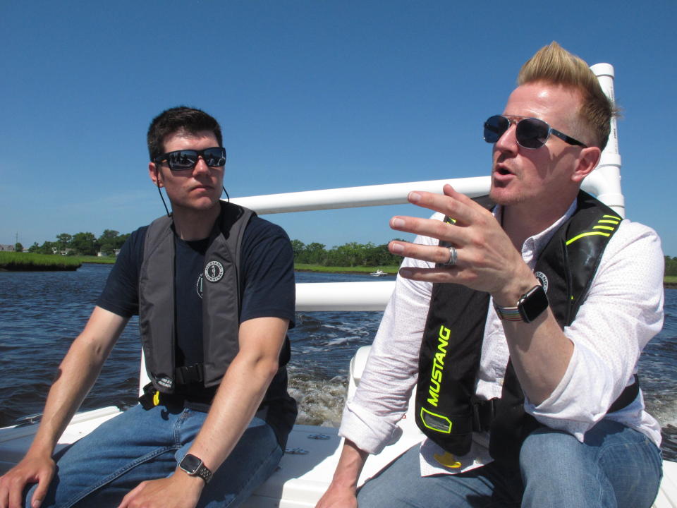 In this June 29, 2021 photo, Scott Stueber, left, a biologist with the New Jersey Department of Environmental Protection, and Shawn LaTourette, right, the department's commissioner discuss the state's program to collect shells from restaurants in Atlantic City and place them into the Mullica River in Port Republic, N.J. while aboard a boat in Port Republic. (AP Photo/Wayne Parry)
