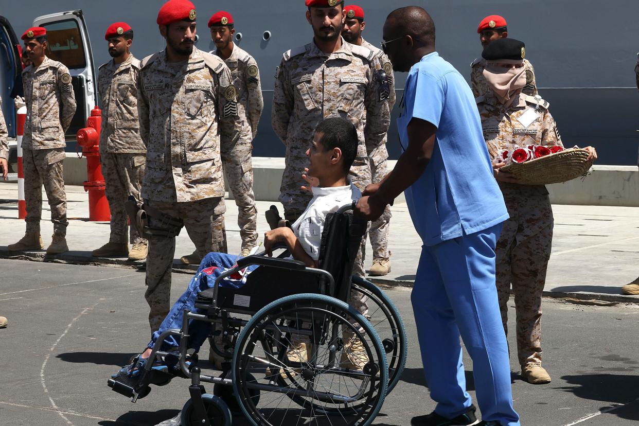 A Saudi medic assists the disabled son of Sudanese Badriah al-Sayed (not pictured) upon arrival in Jeddah on April 30, 2023 following a rescue operation from Port Sudan. (AFP via Getty Images)