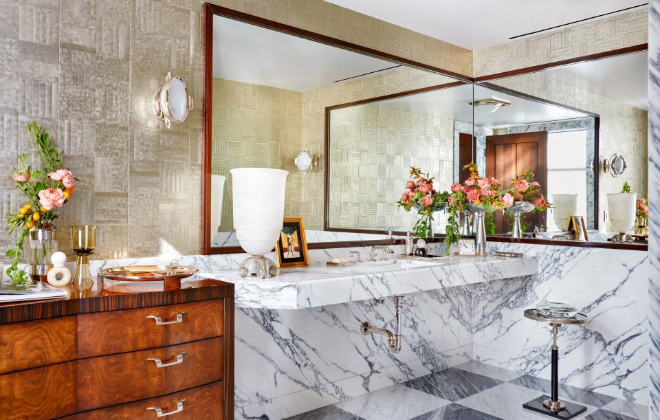 A metallic wall covering by Maya Romanoff brightens the powder room. Sconce by Thomas O’Brien for Visual comfort; custom sink and vanity of arabescato cervaiole marble; Waterworks faucet.
