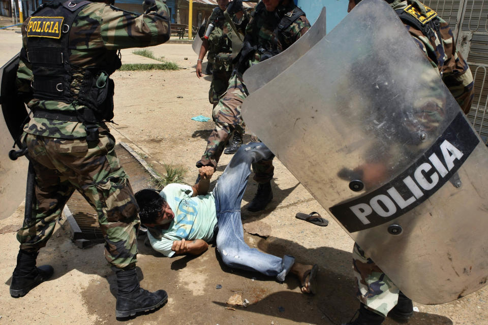 A miner is roughed up by riot police officers during clashes in Puerto Maldonado, Peru, Wednesday, March 14, 2012. Thousands of illegal gold miners battled police for control of a regional capital in the Amazon basin on Wednesday and at least three people were killed by gunfire. The miners are fighting government efforts to regulate small-scale gold extraction, which is ravaging the rain forest, contaminating it with tons of mercury. (AP Photo/ Miguel Vizcarra)