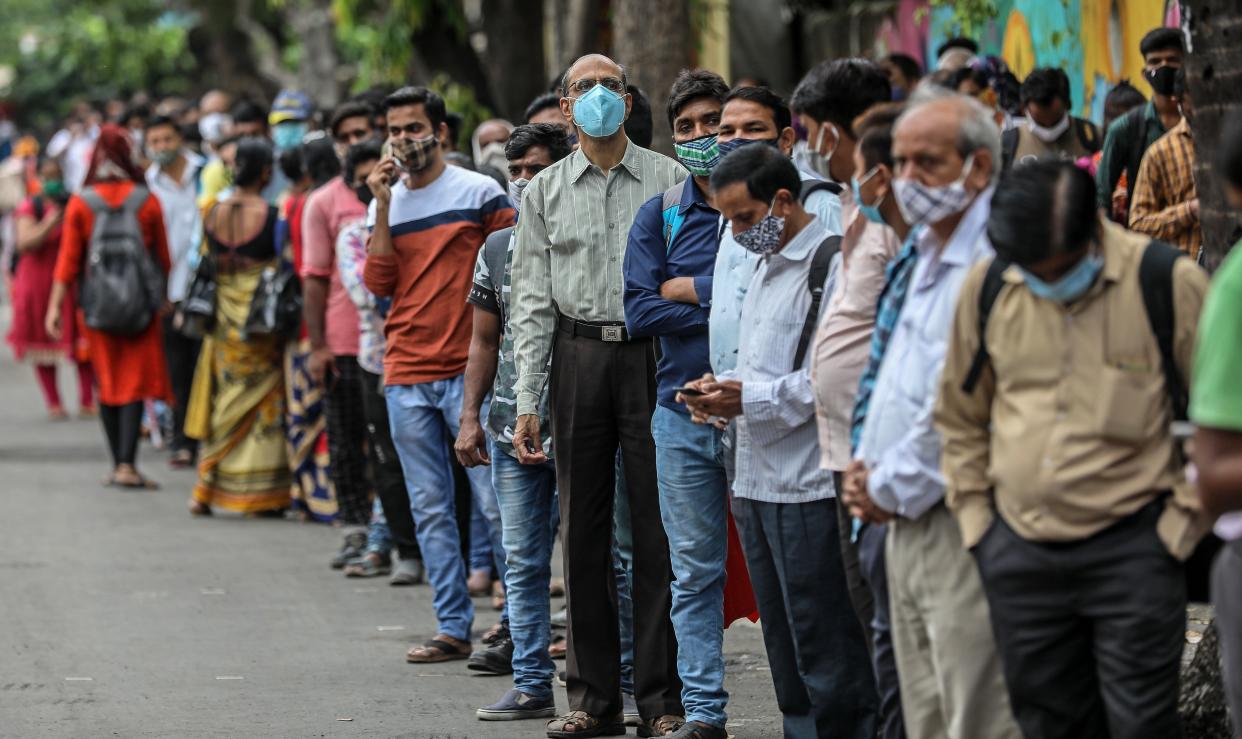 <p>People stand in a queue as they wait for public transport at a bus stop in Mumbai, India, on 8 June, 2021</p> (EPA)