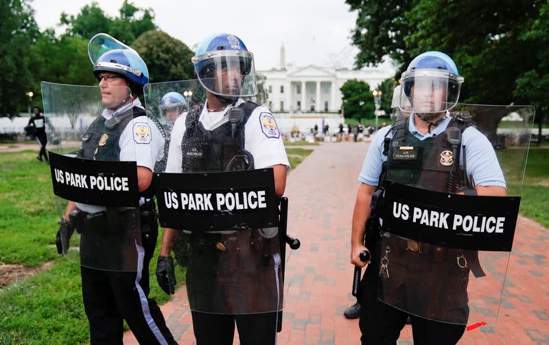 Protestors stand with hands up after clashes between police and protestors attempting to pull down statue of U.S. President Andrew Jackson in front of White House in Washington